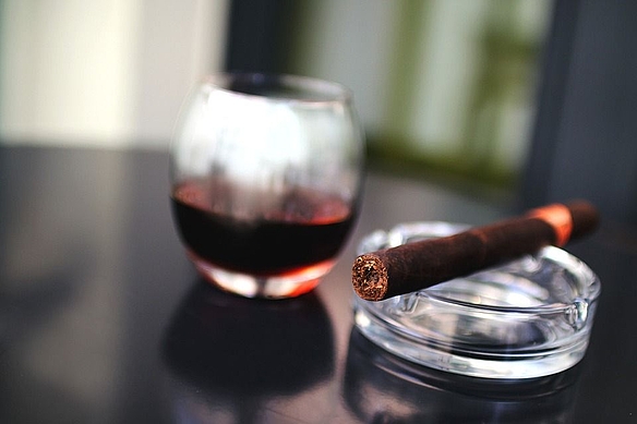 Weinglas und Aschenbecher mit Zigarre auf einem Tisch